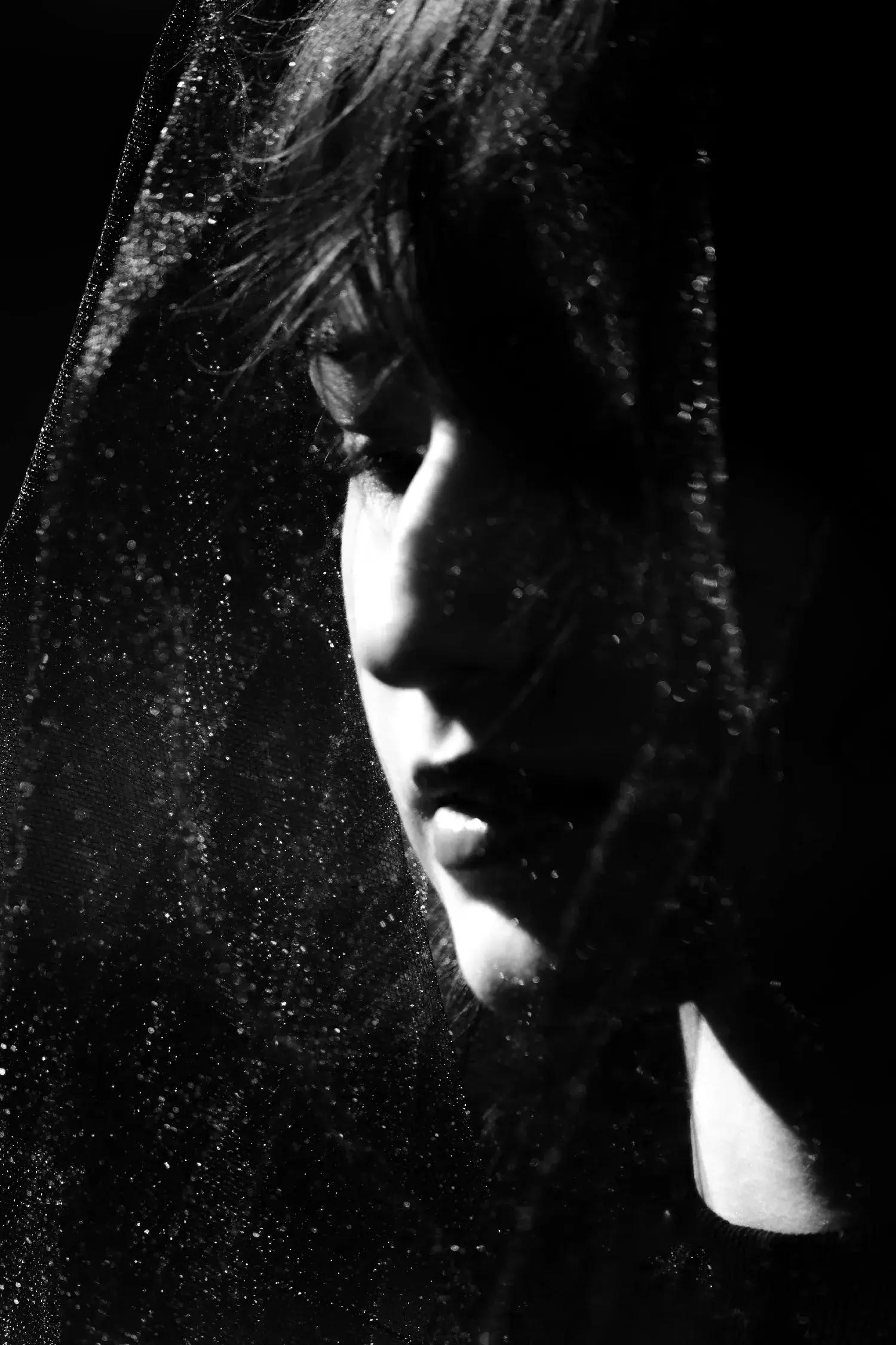 Low key black and white portrait photography of a man face hidden in darkness for moody branding